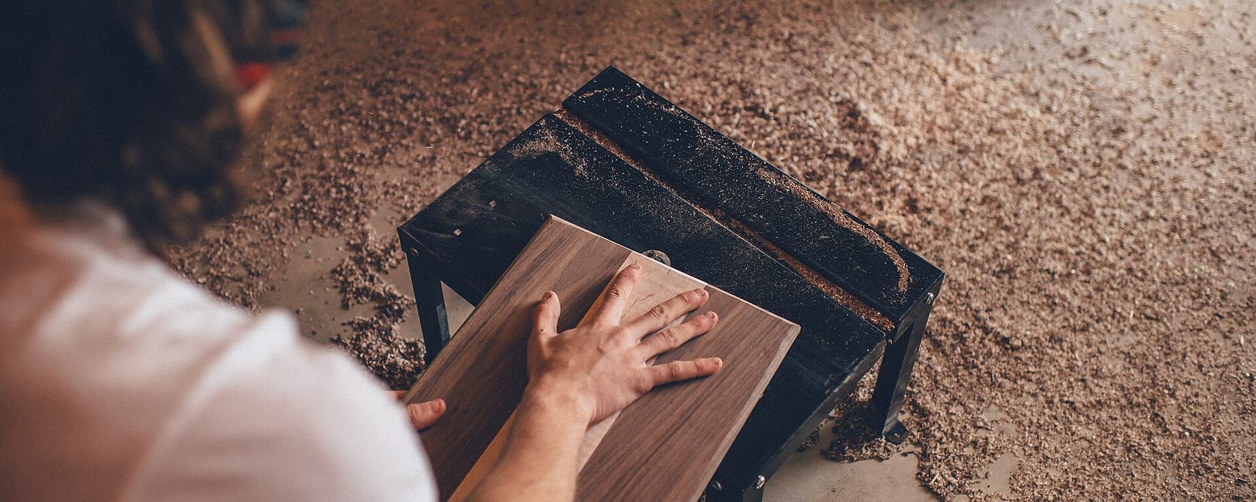 A woodworker shaping a plank at his bench in a workshop