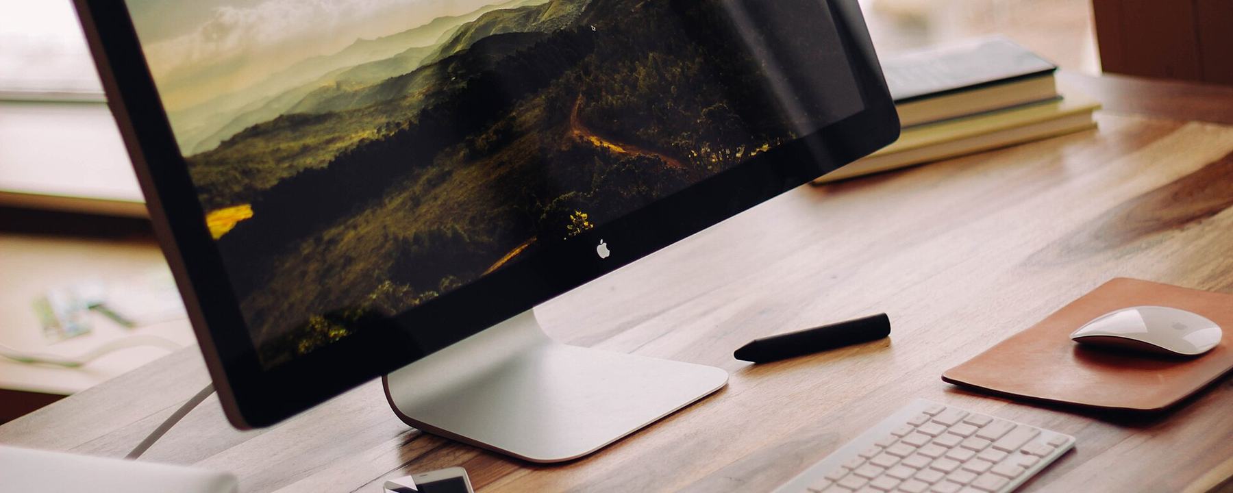 A tidy desk with a monitor, keyboard and a cup of coffee